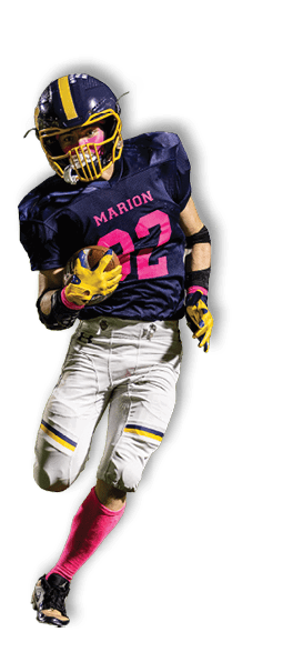 A person wearing a football uniform with a navy blue jersey, white pants, and pink accessories is running on a field while holding a football. Description generated by AI