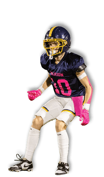 A person wearing a navy blue football uniform with pink gloves and accents is standing on a football field in a ready position. Description generated by AI