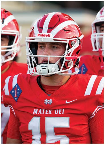 Two people wearing red and white football helmets and uniforms are focused during a game or practice. Description generated by AI