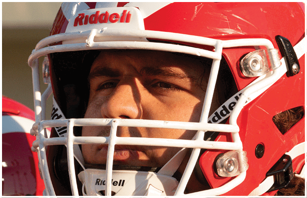 Person wearing a red and white football helmet with a focused expression. Description generated by AI