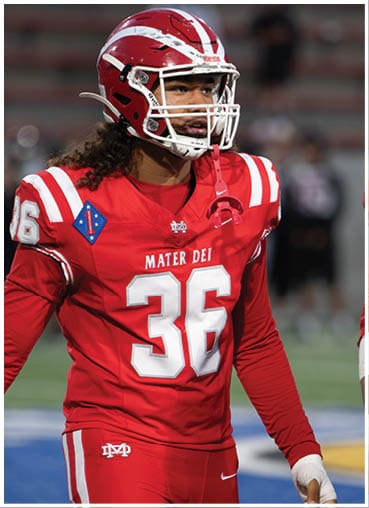 A person wearing a red football uniform with the number 36 and the words Mater Dei on the jersey stands on a field. Description generated by AI