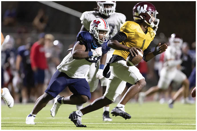 Three football players in blue and white uniforms running on a field. Description generated by AI
