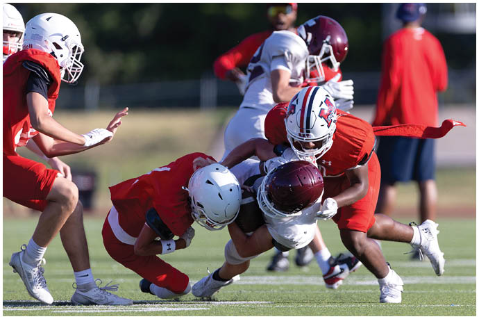 Three football players in blue and white uniforms running on a field. Description generated by AI