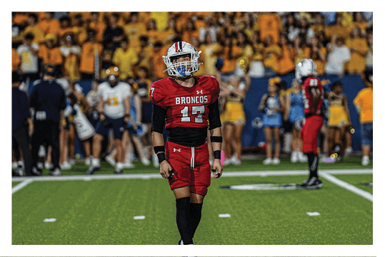 A football player wearing a blue and red jersey. Description generated by AI