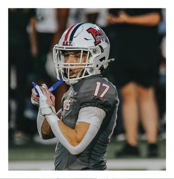 A football player wearing a blue and red jersey. Description generated by AI