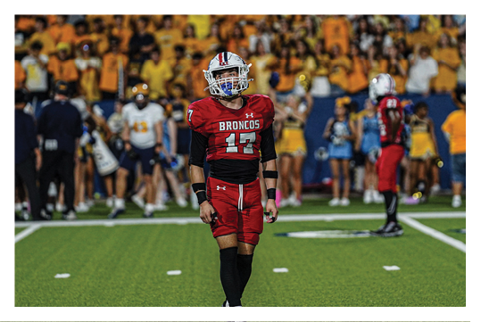 A football player wearing a blue and red jersey. Description generated by AI