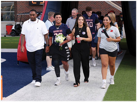 A group of football players wearing black and white uniforms. Description generated by AI