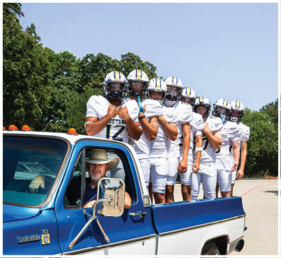 A group of football players huddled together on the field. Description generated by AI
