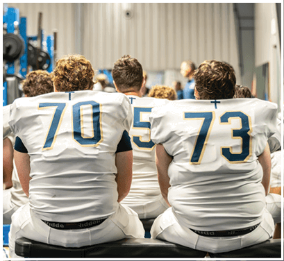 A group of football players huddled together on the field. Description generated by AI