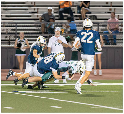 A group of football players huddled together on the field. Description generated by AI