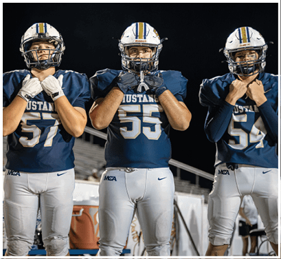 A group of football players huddled together on the field. Description generated by AI