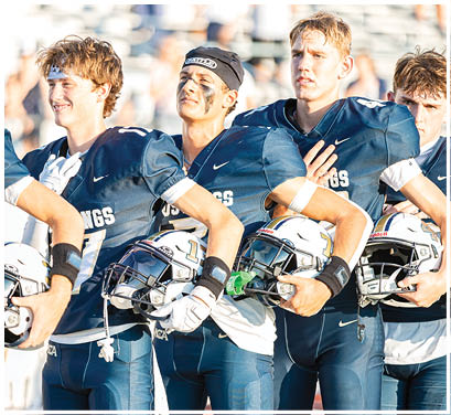 A group of football players huddled together on the field. Description generated by AI