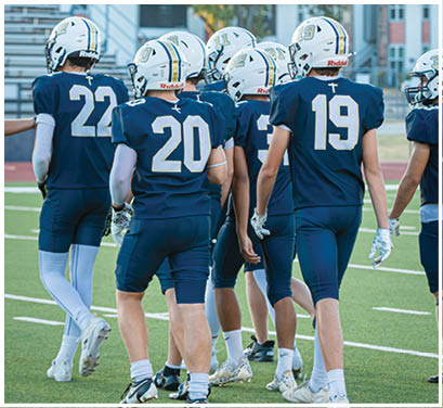 A group of football players huddled together on the field. Description generated by AI
