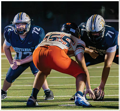 A group of football players huddled together on the field. Description generated by AI