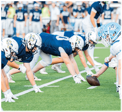 A group of football players huddled together on the field. Description generated by AI