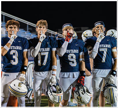 A group of football players huddled together on the field. Description generated by AI