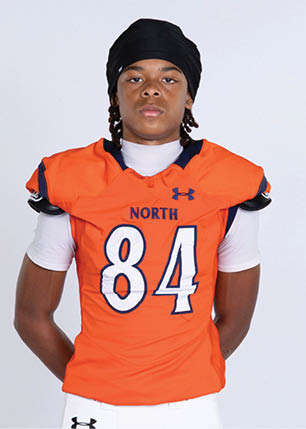 A young man wearing a white and black jersey with the number 14 on it. Description generated by AI