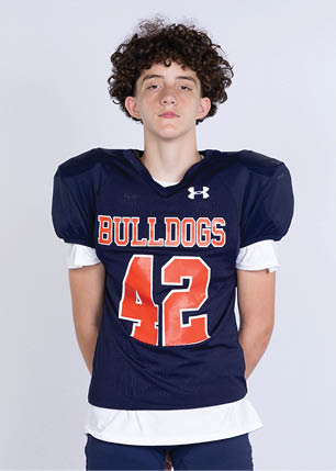 A young man wearing a white and black jersey with the number 14 on it. Description generated by AI