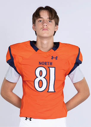 A young man wearing a white and black jersey with the number 14 on it. Description generated by AI