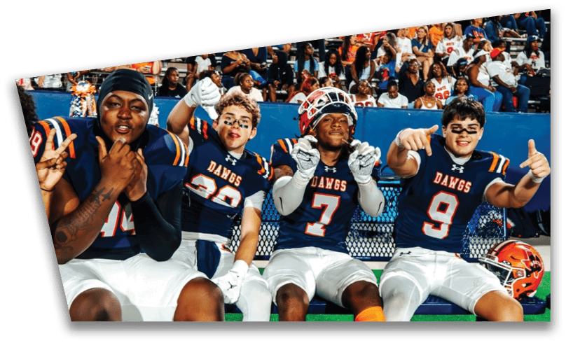 People wearing black American Canyon football uniforms and helmets are standing on a football field at night. Description generated by AI