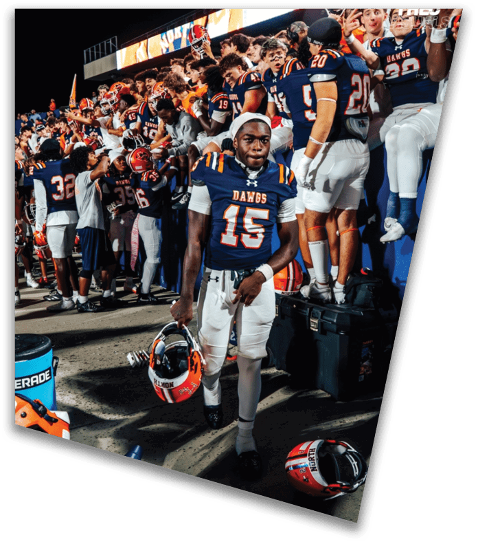 A person wearing a dark football uniform and helmet with “American Canyon" on the jersey is kneeling on one knee on a field at night. Description generated by AI