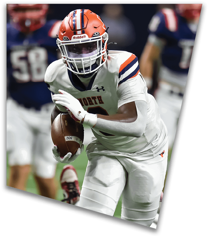 A person wearing a dark football uniform and helmet with “American Canyon" on the jersey is kneeling on one knee on a field at night. Description generated by AI