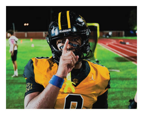 A man in a black jersey is running on a field with a football in his hand. AI generated content