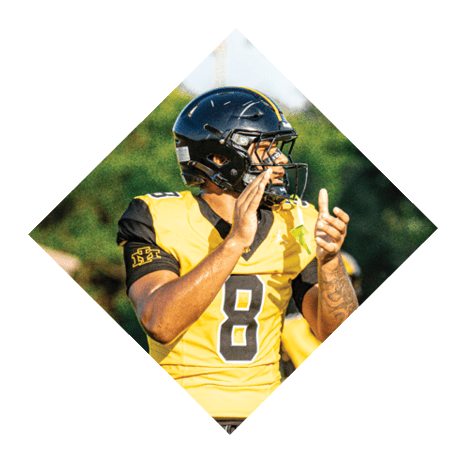 A football player wearing a black jersey with the number 3 kneels on the field. AI generated content
