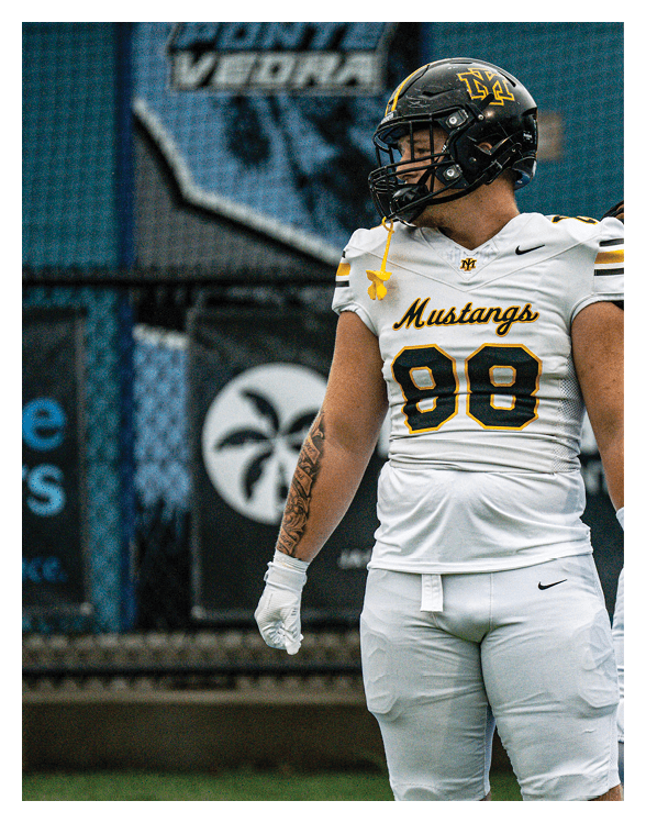 A football player wearing a helmet and white uniform is holding his helmet above his head. AI generated content