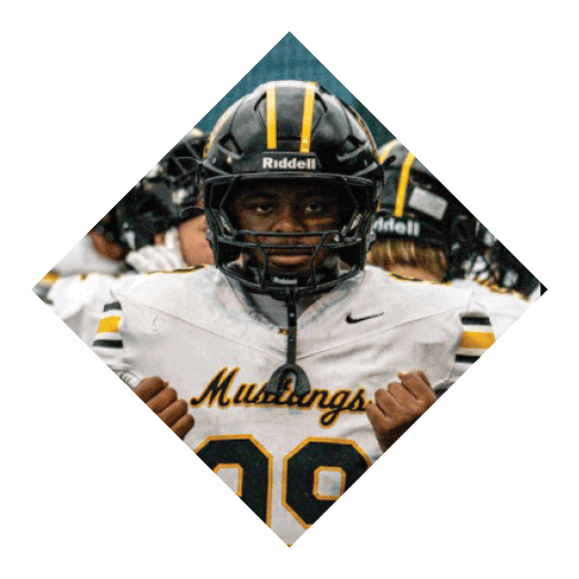 A football player wearing a black jersey with the number 10 sits on the ground with a football helmet on the ground next to him. AI generated content