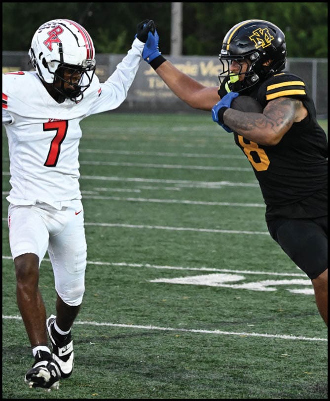 Two people in football uniforms are on a field with one wearing white and the other in black, and they are giving each other a high five. Description generated by AI