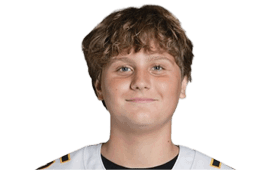 A person with short curly hair is wearing a white sports jersey and smiling slightly against a plain white background. Description generated by AI