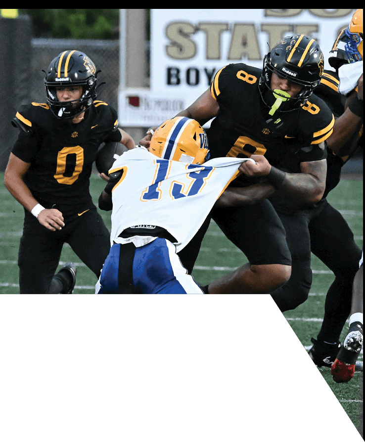 A group of people wearing football uniforms are actively playing on a field with one person in black running while others in white and blue are moving toward them. Description generated by AI