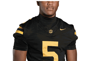 Person wearing a black football jersey with the number five in yellow and a small logo on the chest. Description generated by AI