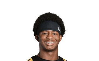 A person with curly hair wearing a black headband and a black sports jersey is smiling. Description generated by AI