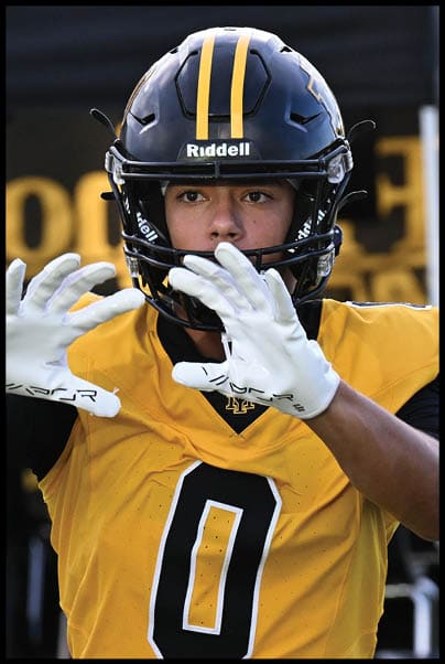 A person wearing a yellow and black football uniform with the number zero is preparing to catch a football during a game or practice. Description generated by AI