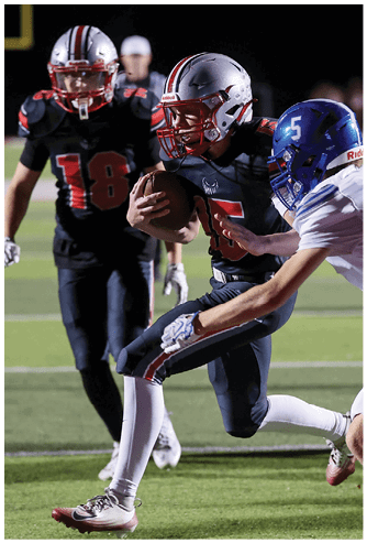 Two people in football uniforms are engaged in a play on a field, with one person in white attempting to tackle another person in black. Descripci n generada con IA