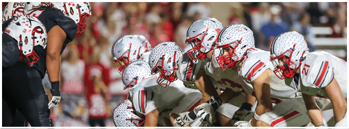 Two opposing American football teams are lined up facing each other on the field, ready for the next play. Descripci n generada con IA