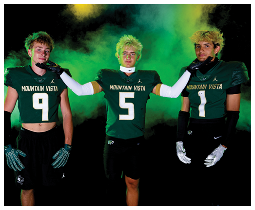 Three people wearing Mountain Vista football uniforms with numbers 9, 5, and 1 pose against a dark background with green and yellow smoke effects. Description generated by AI