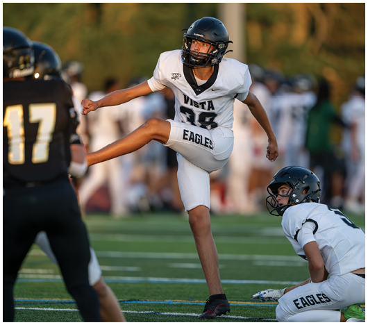 A person in a white football uniform with “Vista Eagles" is kicking a ball toward another person in a black football uniform with the number 17 on the back. Description generated by AI