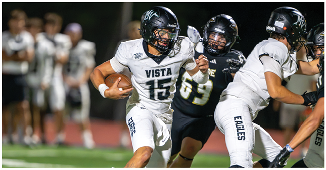 A person wearing a white football uniform with the word Vista and number 15 is running while holding a football tightly. Description generated by AI