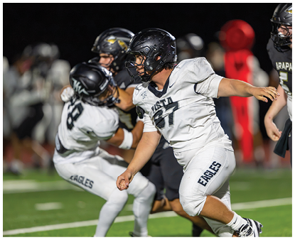 Two people wearing sports uniforms are reaching out toward each other, with one in a white jersey and the other in a black jersey with “ARAPAHOE" and the number 55 visible. Description generated by AI