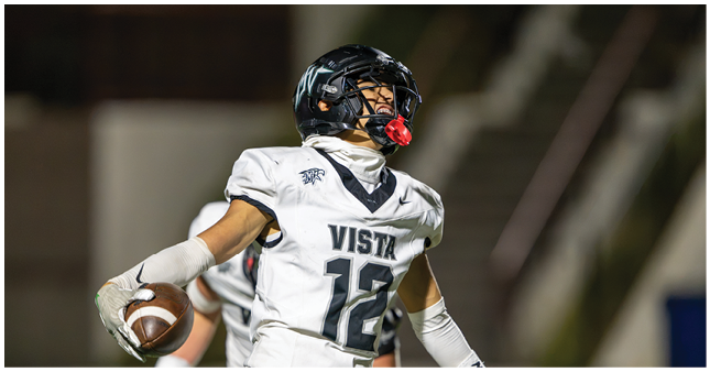 A person wearing a football uniform and helmet is holding a football and appears to be celebrating or shouting on a field at night. Description generated by AI