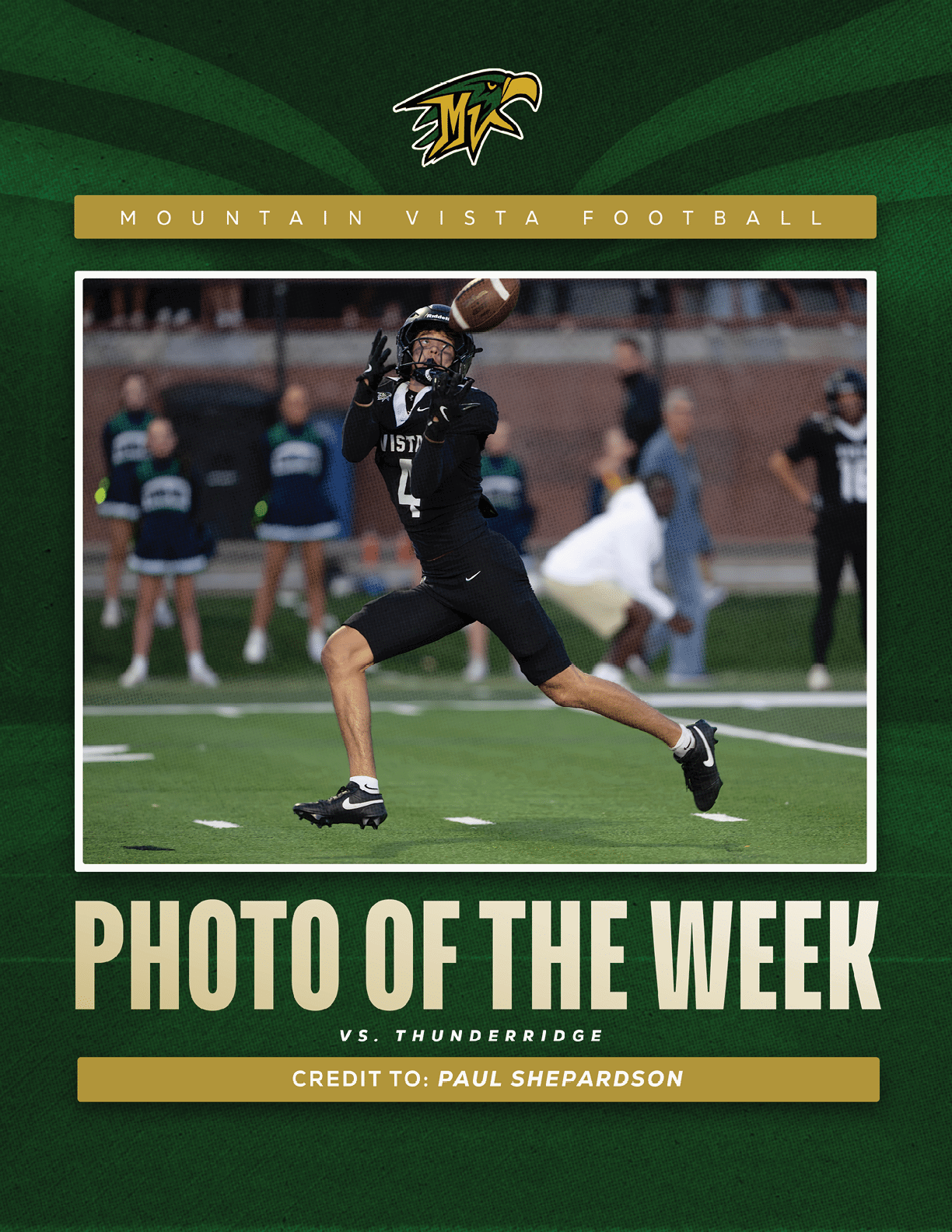 A person in a black football uniform is leaping forward with arms extended to catch a football on a field with blurred people in the background. Description generated by AI