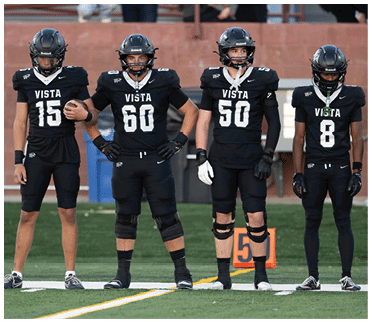 A person wearing a black football uniform with the number 60 and the word Vista on the front is standing with arms outstretched, wearing a black helmet. Description generated by AI