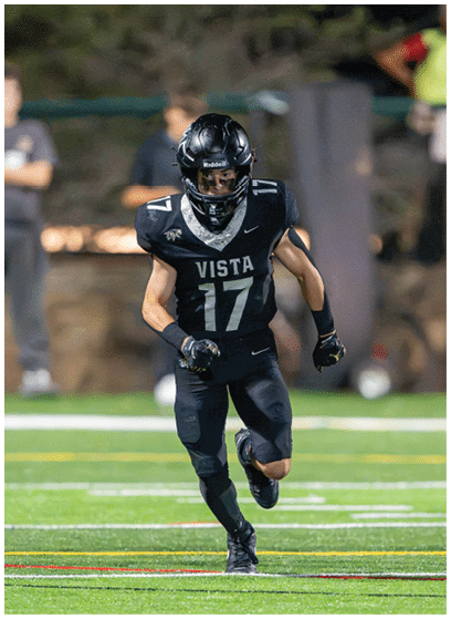 A person wearing a black football uniform with the number 17 and the word Vista on the front is running on a field. Description generated by AI
