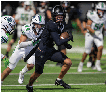 A person in black athletic gear is running with a football while two people in white uniforms chase them on a football field. Description generated by AI