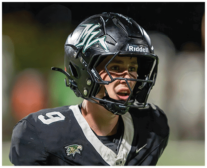 A person wearing a black football helmet and uniform with the number nine and an eagle logo is looking to the side with an open mouth, appearing focused or engaged. Description generated by AI