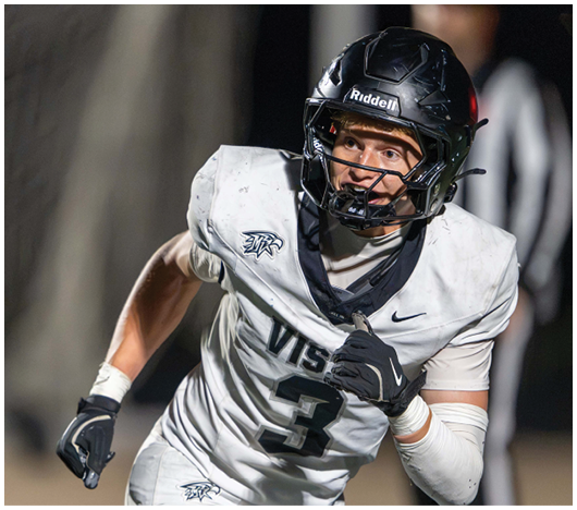 A person wearing a white football uniform with the number three and a black helmet is running on a field during a game. Description generated by AI