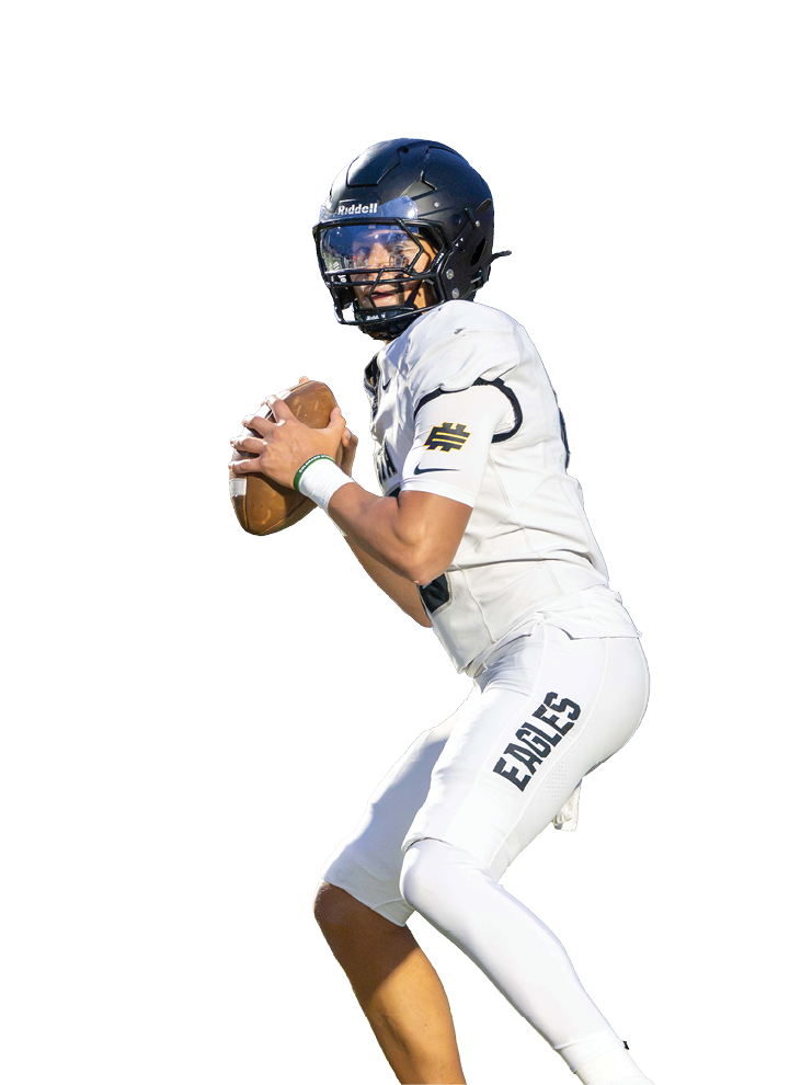 A person wearing a dark helmet and white football uniform with the word Eagles on the pants is holding a football in a ready-to-throw position. Description generated by AI